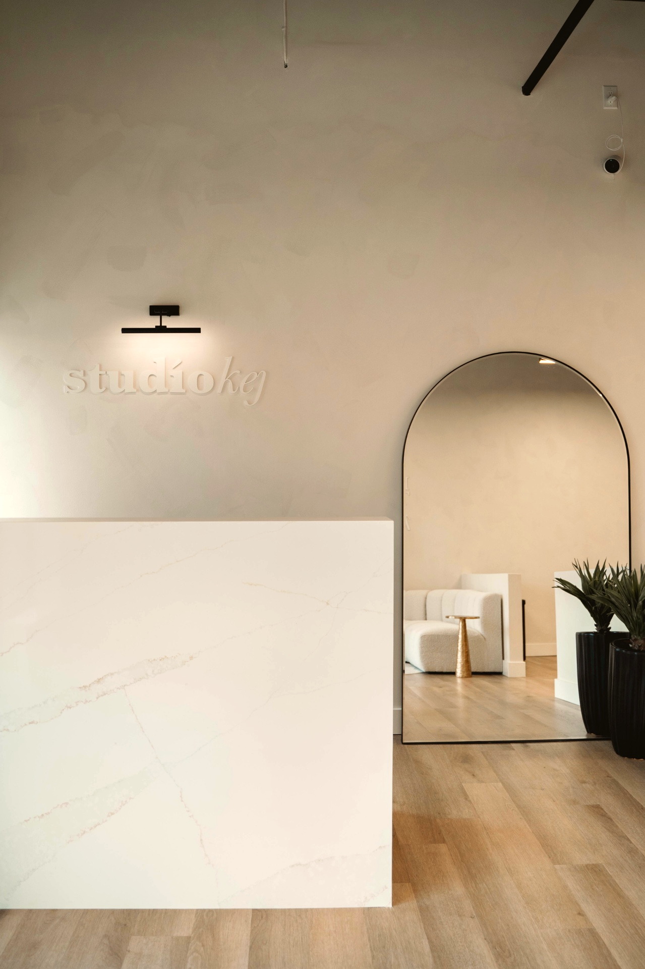 Studio KEJ reception with the studio kej wordmark, arched mirror and warm oak floors
