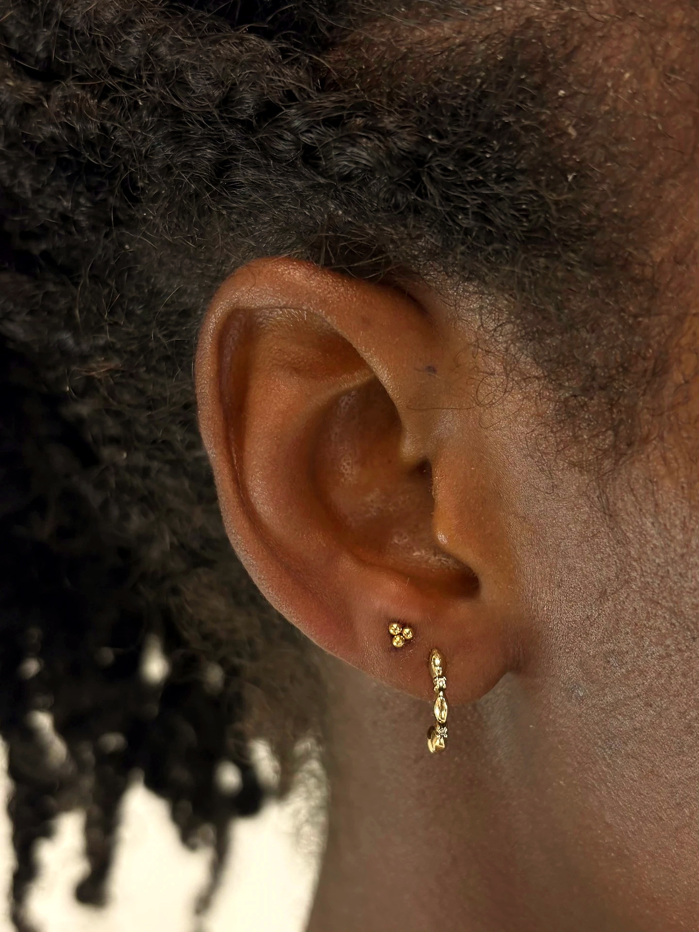 Delicate gold lobe piercings